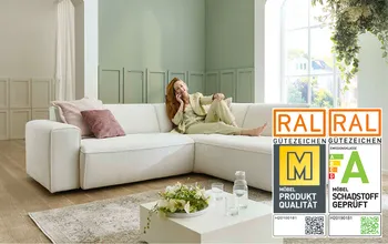 Frau sitzt beim telefonieren auf einem weißem Ecksofa mit Kissen